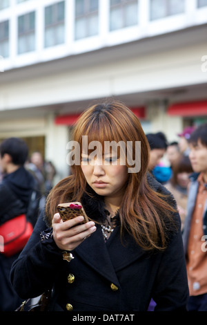 Giovane donna con un telefono cellulare al di fuori della stazione di Shibuya 2012 Foto Stock