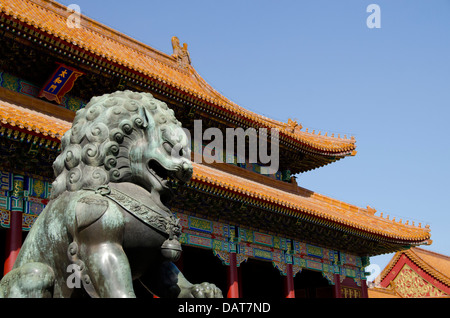 Cina, Pechino, Città Proibita (aka Zijin Cheng). Bronzo leone mitologico statua con piastrelle di ceramica sul tetto del palazzo in distanza. Foto Stock