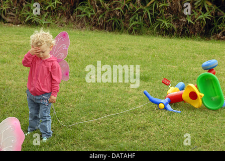 Stupiti bambina giocando con colorati di triciclo Foto Stock