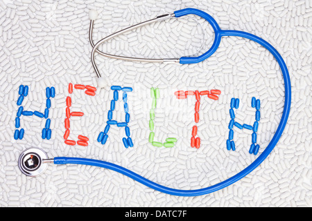 Salute testo parola fatta di compresse e pillole di farmaci di diversi colori messi insieme come mosaico con uno stetoscopio Foto Stock