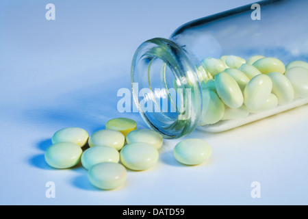 Close-up di farmaci, piccolo giallo compresse diffusa dalla bottiglia con il tablet sul tavolo Foto Stock