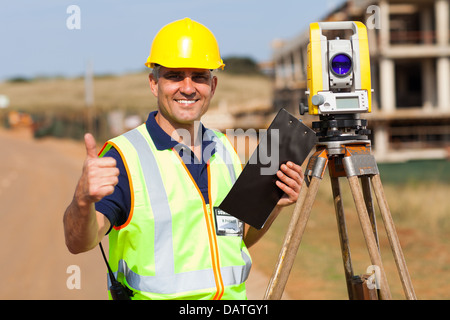 Senior surveyor dando pollice in alto sul sito in costruzione Foto Stock