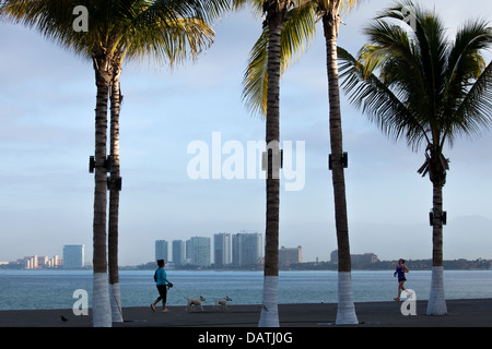 I corridori e Walkers sul Puerto Vallarta boardwalk di sunrise, Messico. Foto Stock