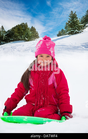 Felice, sorridente ragazza seduta sulla slitta sulla slitta nella foresta Foto Stock