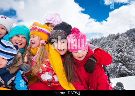 Gruppo di diversità cercando contenti i bambini abbracciando e giocare insieme su inverno giornata di sole Foto Stock