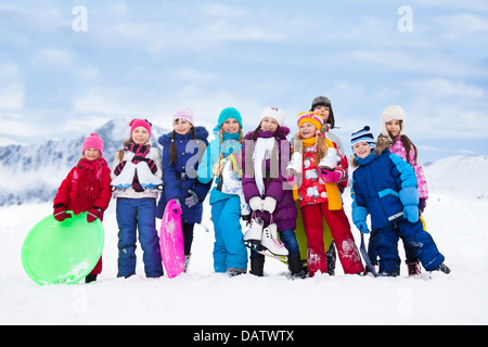 Gruppo di bambini insieme al di fuori nella neve con slitta, pattini da ghiaccio divertendosi con attività invernali Foto Stock