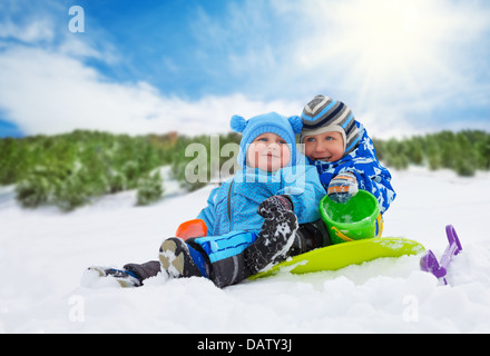Due ragazzi piccoli fratelli seduti sulla neve e giocare insieme sulla giornata invernale Foto Stock
