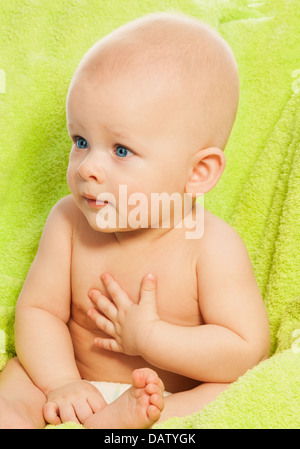 Sorpreso ragazzino con una forte espressione sedersi sul verde Sedia bambino Foto Stock