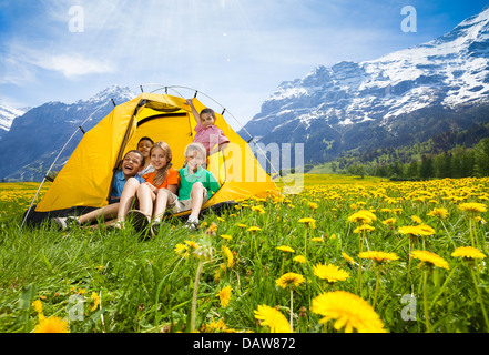 Gruppo di bambini, ragazzi e ragazze seduti insieme in tenda nel campo di tarassaco Foto Stock