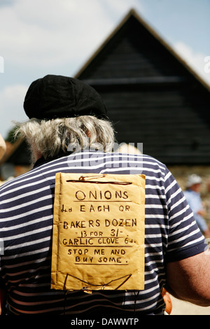 Onion venditore carattere con il prezzo di listino sulla sua schiena. Foto Stock