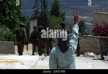 Nablus, West Bank, Territorio palestinese. 19 Luglio, 2013. Una donna Palestinese lampeggia in segno di vittoria come lei grida a forze di sicurezza israeliane durante scontri a seguito di una protesta contro l'espropriazione delle terre palestinesi da parte di Israele del 19 luglio 2013 nel villaggio di Kfar Qaddum, vicino la Cisgiordania occupata città di Nablus Credito: Nedal Eshtayah APA/images/ZUMAPRESS.com/Alamy Live News Foto Stock