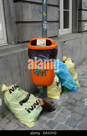 Sacchi spazzatura / cestino sacchetto con i rifiuti domestici davanti la casa e litterbin sul marciapiede in strada di città Foto Stock