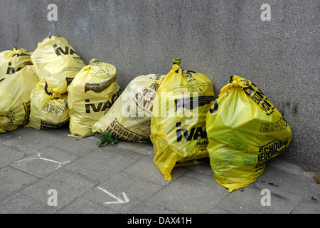 Sacchi spazzatura / cestino sacchetto con i rifiuti domestici sul marciapiede davanti alla casa in via della città Foto Stock