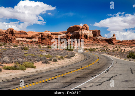 La strada si snoda attraverso i monumenti di pietra arenaria del Parco Nazionale di Arches, Moab, Utah Foto Stock