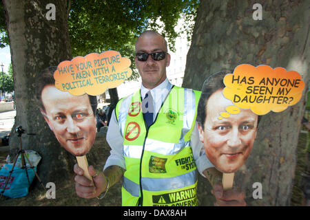 Londra, Regno Unito. Il 19 luglio 2013. Un manifestante al di fuori di Downing street trattiene le maschere di carta del Primo Ministro David Cameron di sollevare il problema dei bambini che vengono presi in cura dai servizi sociali contro la volontà dei genitori Credito: amer ghazzal/Alamy Live News Foto Stock