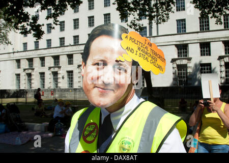 Londra, Regno Unito. Il 19 luglio 2013. Un manifestante al di fuori di Downing street indossa una maschera di carta raffigurante il Primo Ministro David Cameron come " un terrorista politico che ruba i bambini" per sollevare il problema dei bambini che vengono presi in cura dai servizi sociali contro la volontà dei genitori Credito: amer ghazzal/Alamy Live News Foto Stock