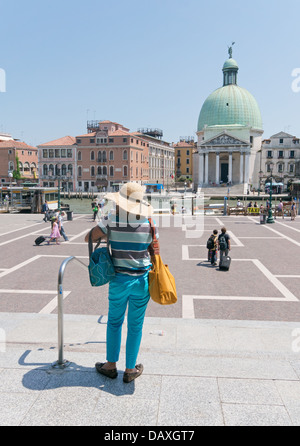 La donna nel cappello di paglia fuoriesce dalla stazione ferroviaria Santa Lucia di Venezia e vede il Grand Canal e San Simeon Piccolo chiesa Foto Stock