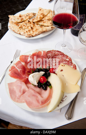 Salame, prosciutto, mozzarella, formaggi e melone, antipasti servita con vino rosso e focacce, Roma, Italia Foto Stock