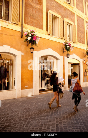 Due donne a piedi giù per una strada nel quartiere dello shopping di Roma, Italia Foto Stock