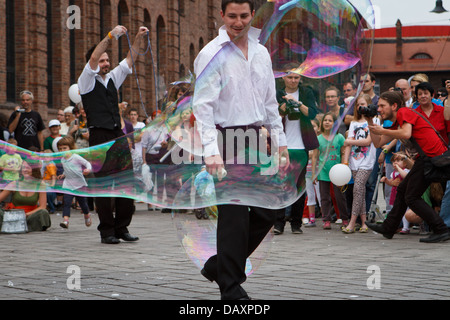 Artisti facendo grandi bolle di sapone durante "Industriada' 2013 street performance a Nikiszowiec piazza principale. Katowice in Polonia. Foto Stock