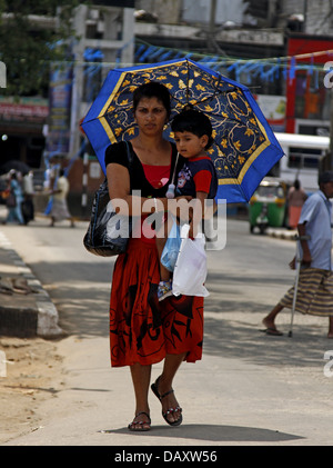 Donna con bambino & ombrello PERADENIYA SRI LANKA 12 Marzo 2013 Foto Stock