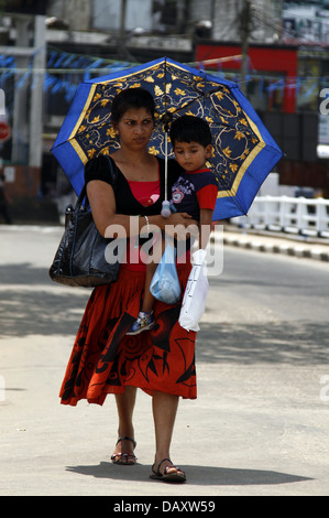 Donna con bambino & ombrello PERADENIYA SRI LANKA 12 Marzo 2013 Foto Stock