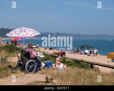 Uomo in sedia a rotelle godendo una giornata in spiaggia, Slapton Sands, Devon, Regno Unito 2013 Foto Stock