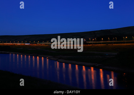 Autostrada M62 al tramonto riflesso in legno stand serbatoio, Rishworth, West Yorkshire Foto Stock
