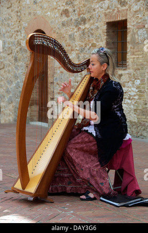La donna che suona l'arpa in cortile San Gimignano Toscana Italia Foto Stock