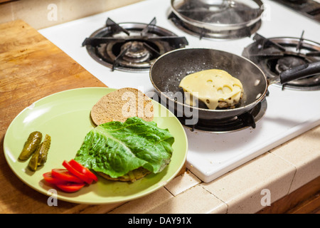 Una lauta turchia hamburger con basso contenuto di grassi di formaggio svizzero e il pane sottile round con sottaceti grigliate di cipolla pomodoro e lattuga romana Foto Stock