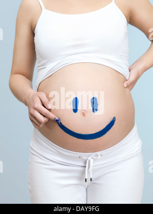 Donna incinta il disegno di una faccina felice faccia sul suo ventre Foto Stock