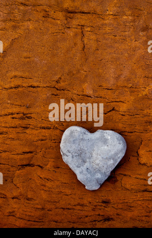 Forma di cuore pebble su roccia arenaria colorata da depositi di ferro da una metropolitana fonte di acqua Foto Stock