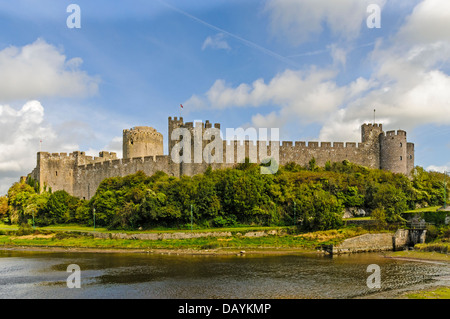 La cortina esterna pareti di Pembroke Castle protetti da torri formidabile e arbusti denso come si vede da tutta l'estuario Foto Stock