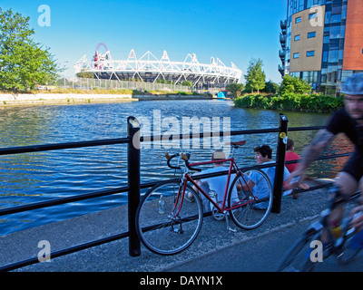 Maschio di escursioni in bicicletta lungo il fiume Lea (Lee) Navigazione, Hackney Wick che mostra lo Stadio Olimpico e ArcelorMittal orbita in distanza Foto Stock