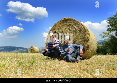 Coppia senior in appoggio contro una balla di fieno Reggio Emilia colline in Italia la Regione Emilia Romagna Foto Stock