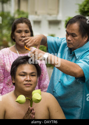 Bangkok, Tailandia. 21 Luglio, 2013. Un giovane uomo di famiglia taglia i capelli prima che egli divenne ordinati come un monaco buddista di Wat Benchamabophit sul primo giorno del Vassa, i tre mesi di ritiro annuale osservata dai monaci Theravada e monache. Gli uomini spesso immettere il monastero e diventare monaci per Vassa. Il primo giorno di Vassa (o la Quaresima buddista) molti buddisti visita i loro templi a ''make merito.'' durante Vassa, monaci e monache rimangono all' interno dei monasteri e tempio motivi, dedicando il proprio tempo a intensivo di meditazione e di studio. Foto Stock