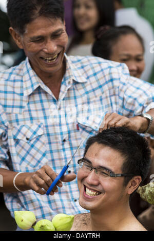 Bangkok, Tailandia. 21 Luglio, 2013. Un giovane uomo di famiglia taglia i capelli prima che egli divenne ordinati come un monaco buddista di Wat Benchamabophit sul primo giorno del Vassa, i tre mesi di ritiro annuale osservata dai monaci Theravada e monache. Gli uomini spesso immettere il monastero e diventare monaci per Vassa. Il primo giorno di Vassa (o la Quaresima buddista) molti buddisti visita i loro templi a ''make merito.'' durante Vassa, monaci e monache rimangono all' interno dei monasteri e tempio motivi, dedicando il proprio tempo a intensivo di meditazione e di studio. Foto Stock