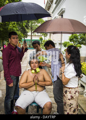 Bangkok, Tailandia. 21 Luglio, 2013. Un giovane uomo di famiglia taglia i capelli sotto un ombrello durante una pioggia prima divenne ordinati come un monaco buddista di Wat Benchamabophit sul primo giorno del Vassa, i tre mesi di ritiro annuale osservata dai monaci Theravada e monache. Gli uomini spesso immettere il monastero e diventare monaci per Vassa. Il primo giorno di Vassa (o la Quaresima buddista) molti buddisti visita i loro templi a ''make merito.'' durante Vassa, monaci e monache rimangono all' interno dei monasteri e tempio motivi, dedicando il proprio tempo a intensivo di meditazione e di studio. Foto Stock