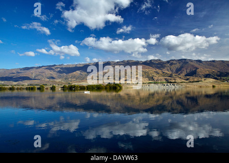 Il lago di Dunstan, Pisa di gamma e di persone in barca da pesca di Central Otago, Isola del Sud, Nuova Zelanda Foto Stock