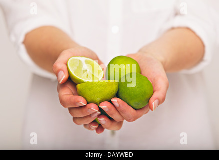 Donna con una manciata di fettine di lime aspro Foto Stock