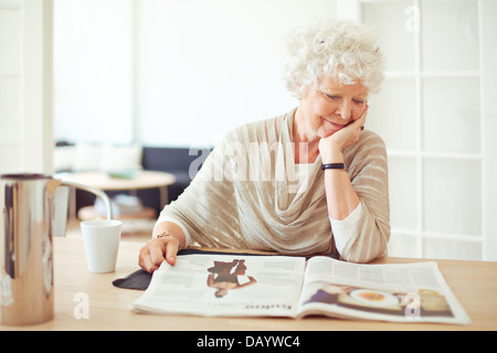 Elegante nonna seduti a casa leggendo una rivista Foto Stock