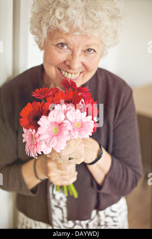 Sorridente donna senior tenendo un mazzo di fiori Foto Stock