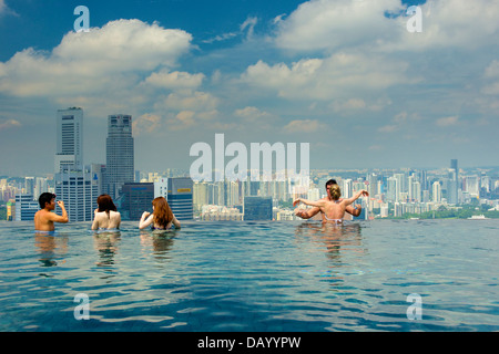 Gli ospiti del Marina Bay Sands godendo un imbibire a posta sul tetto dell'hotel piscina infinity e tenendo le attrazioni di Singapore lo skyline di Foto Stock