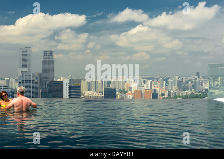 Gli ospiti del Marina Bay Sands godendo un imbibire a posta sul tetto dell'hotel piscina infinity e tenendo le attrazioni di Singapore Foto Stock