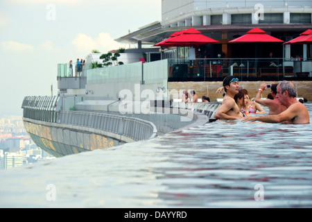 Gli ospiti del Marina Bay Sands godendo un imbibire a posta sul tetto dell'hotel piscina infinity e tenendo le attrazioni di Singapore Foto Stock