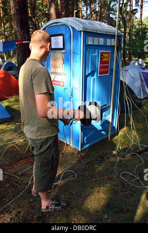 Un partecipante del 'Chaos Communication Camp 2007' sorge nella parte anteriore di un 'Data Loo', una trasformata WC cassetta contenente collegamenti dei cavi di rete, sui composti del Museo dell'aviazione ("Luftfahrtmuseum') Finowfurt, Germania, 9 agosto 2007. Circa 1.200 appassionati di computer da Germania e altrove si sono riuniti per cinque giorni i Summer Camp, che vede se stessa come 'open air fest Foto Stock