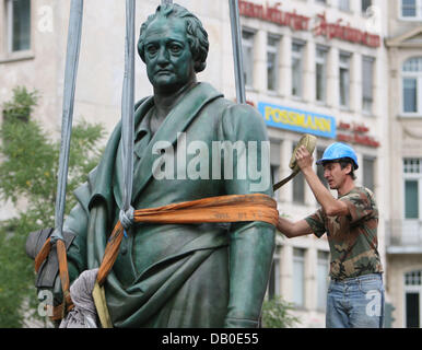 Una gru viene utilizzata per il sollevamento di una statua di Johann Wolfgang von Goethes in suo luogo presso il Goethe square a Francoforte sul Meno, Germania, 13 agosto 2007. Dopo mesi di restauri la statua di il figlio più famoso di Francoforte è stato rimesso al suo posto. La statua rimarrà coperto fino a quando i poeti 258th compleanno il 28 agosto quando le staue saranno presentati al pubblico. Foto: Boris Ro Foto Stock