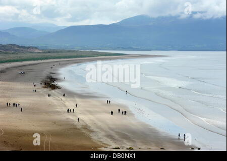 La gente a piedi su Giugno 18, 2013, lungo la spiaggia di pollice vicino a pollice (Counnty Kerry) sulla penisola di Dingle nella parte sud-ovest dell'Irlanda. Background: montagne della penisola di Iveragh. Foto Stock