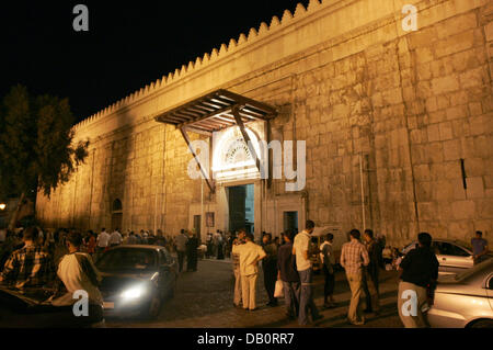 Supporto di persone al di fuori di un entrancce al illuminato Umayyad moschea, la Grande Moschea di Damasco, Siria, 29 agosto 2007. Moschea degli omayyä di, che si trova alla fine del al-Hamidiyeh souq nella città vecchia di Damasco, fu costruito nel 705 D.C. dagli Umayyad califfo Al-Walid I quando Damasco era la capitale dell'Impero arabo. Foto: Rainer Jensen Foto Stock