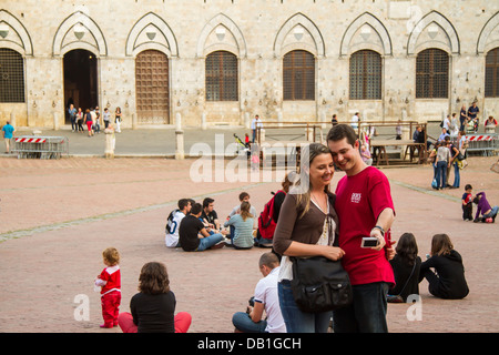 Coppia giovane tenendo la propria fotografia sulla famosa destinazione turistica di Piazza del Campo a Siena, Toscana, Italia, Europa Foto Stock